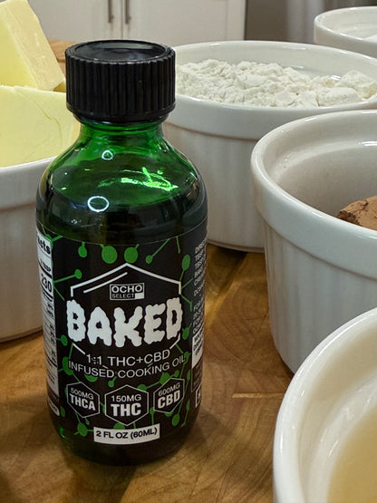Green bottle labeled 'Baked' on a kitchen counter with white containers in the background